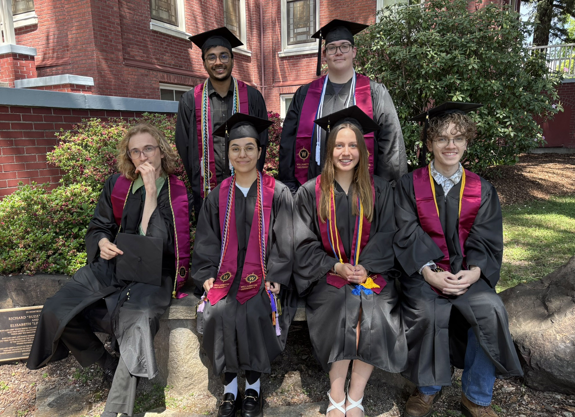 Willamette scholarship recipients in graduation regalia outside of Waller Hall